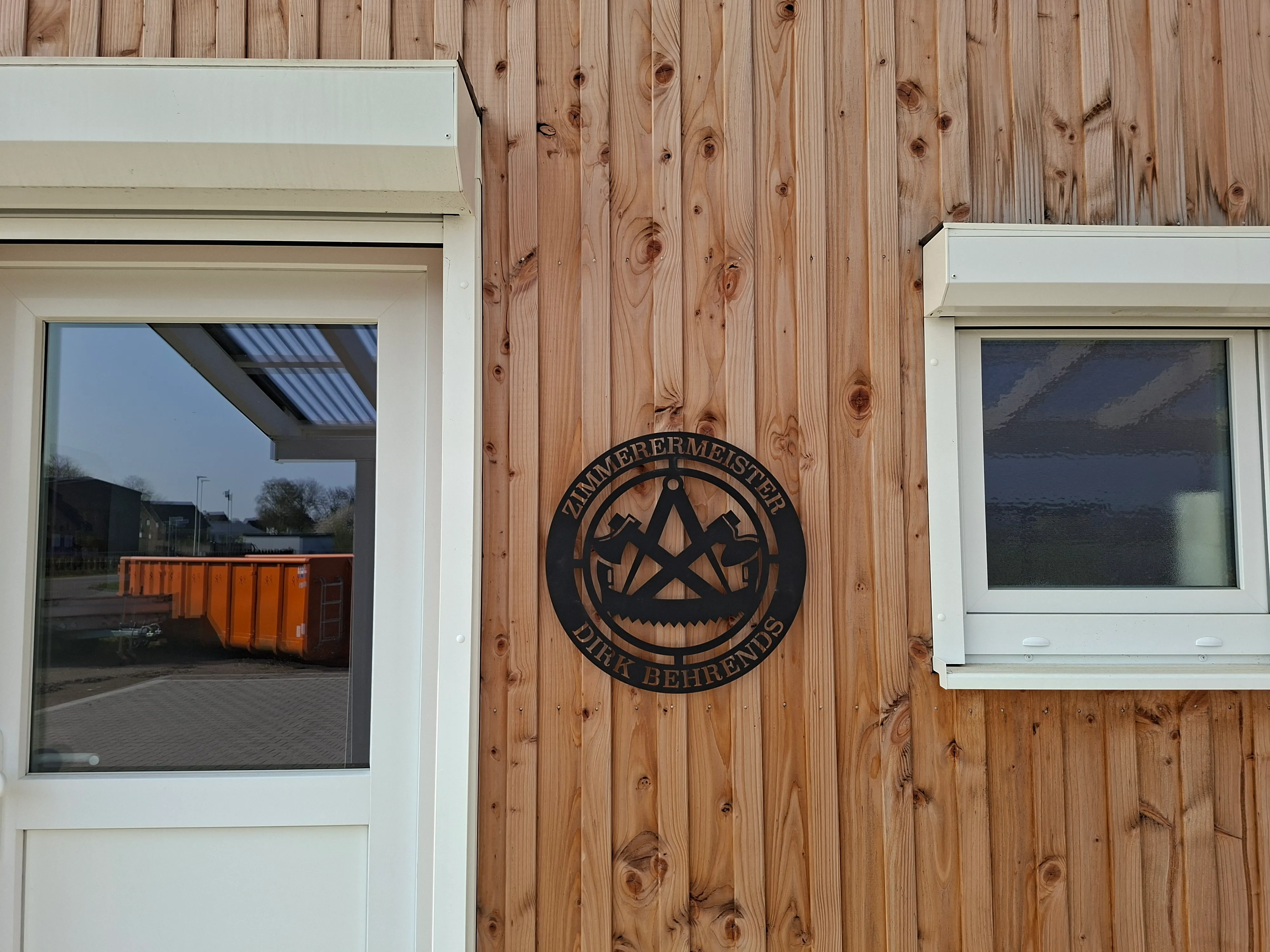 Emblem Zimmerermeister Dirk Behrends an der Holzfassade