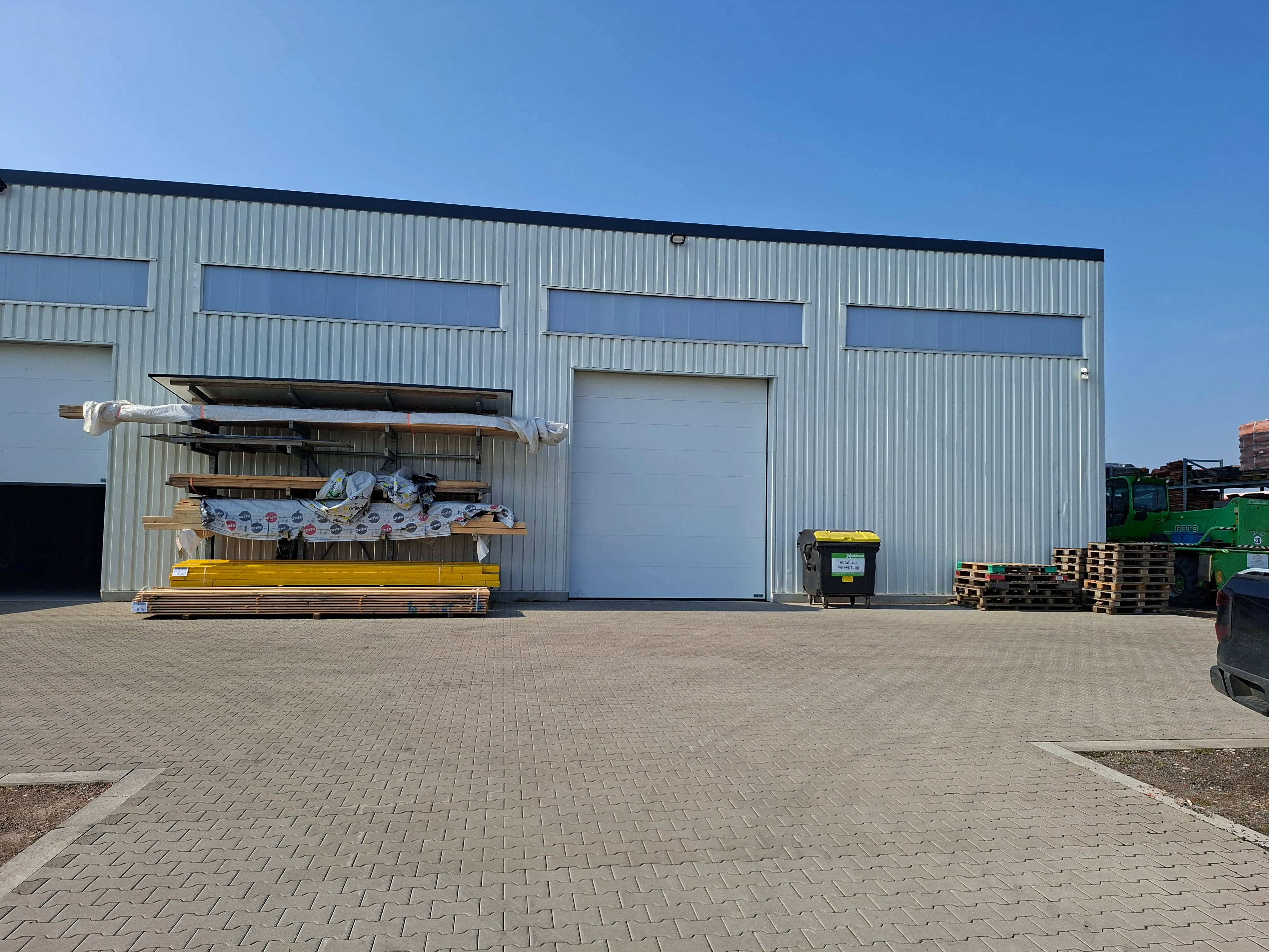 Firmenhalle mit Tor und gelagertem Bauholz