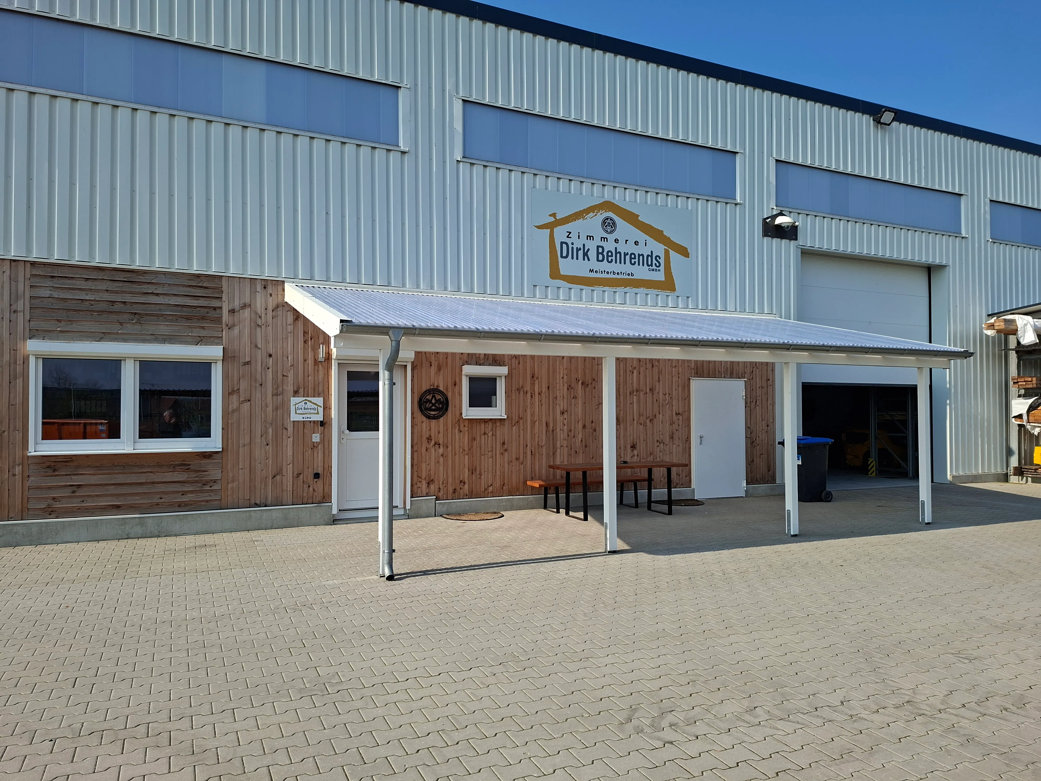 Überdachter Eingangsbereich der Zimmerei mit Firmenschild
